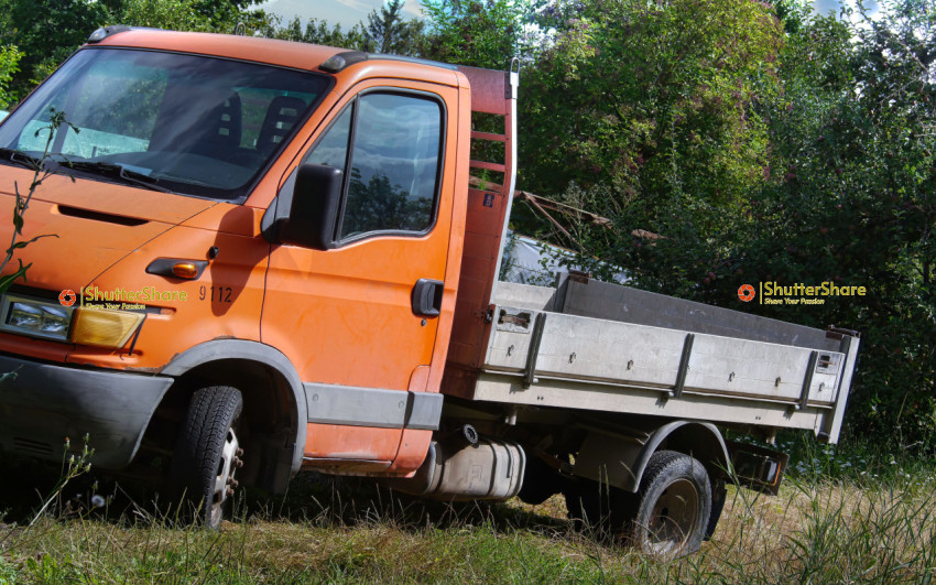 Orange Iveco Daily Flatbed Truck Parked in a Field