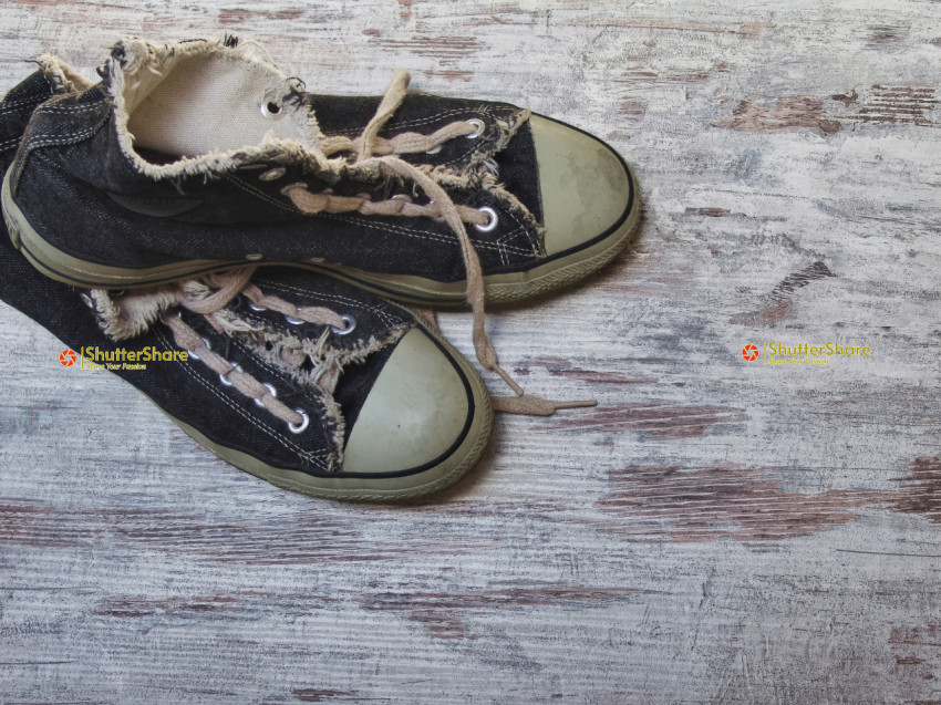 Pair of Worn Black Sneakers on Distressed Wooden Surface