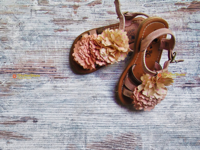 Pair of Flower-Embellished Sandals on Distressed Wooden Surface