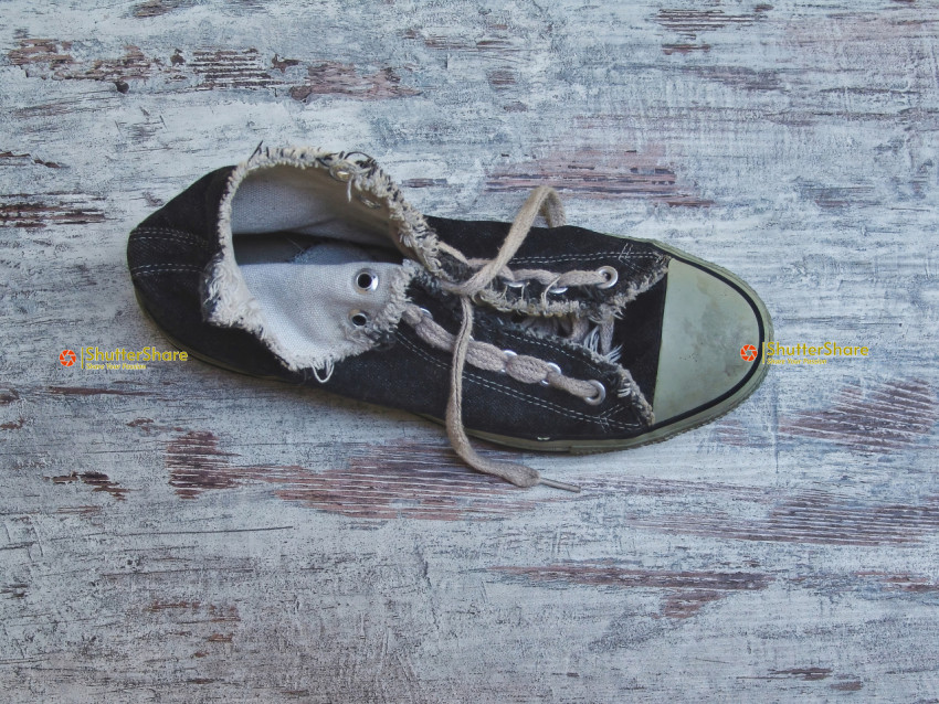 Single Worn Black Sneaker on Distressed Wooden Surface