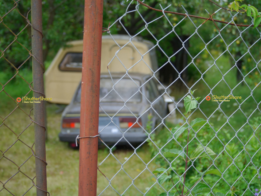 Rusty Fence with Glimpse of Abandoned Vehicles